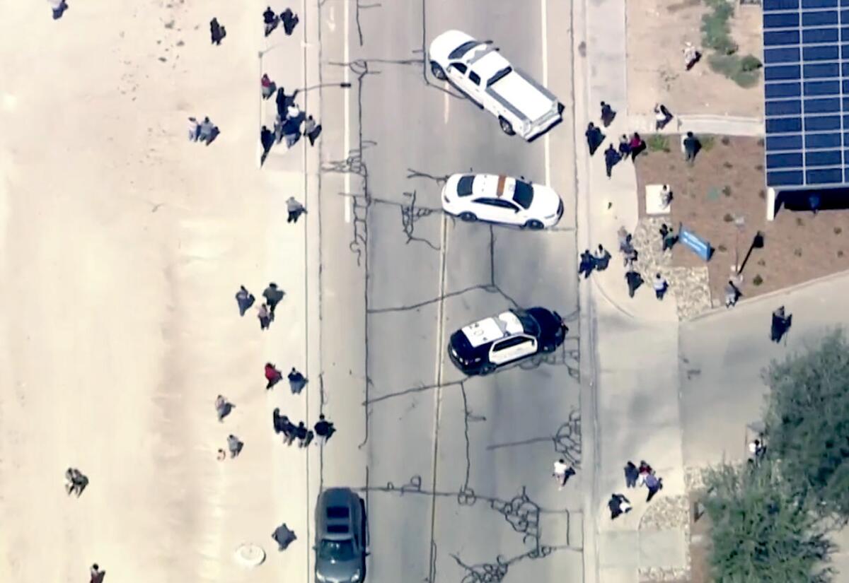 An overhead shot of cars in a road and people walking near them.