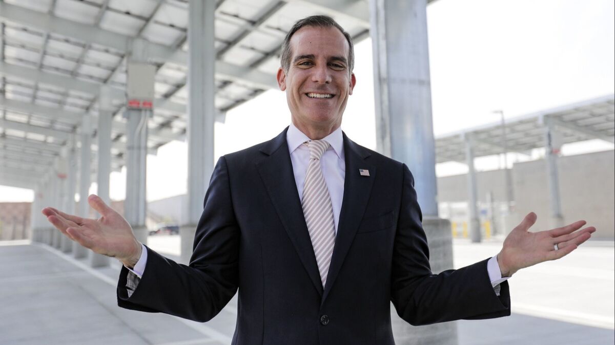 Mayor Eric Garcetti stands under the solar power system at Los Angeles Department of Transportation bus depot in downtown Los Angeles. Critics question whether he's being realistic about how the homelessness crisis is hurting the city.