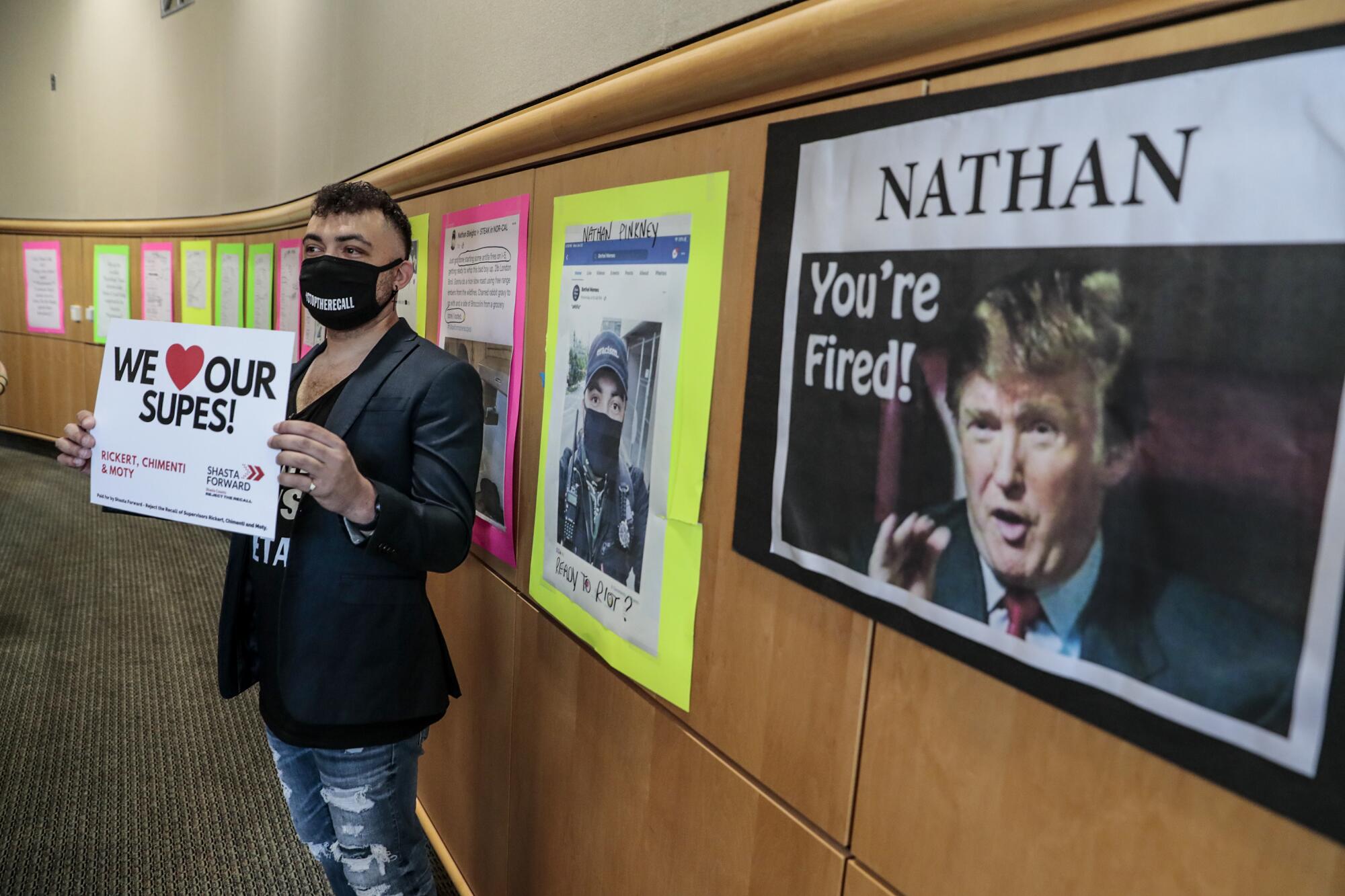 Nathan Pinkney  in front of a wall filled with posters showing his  social media posts and court records