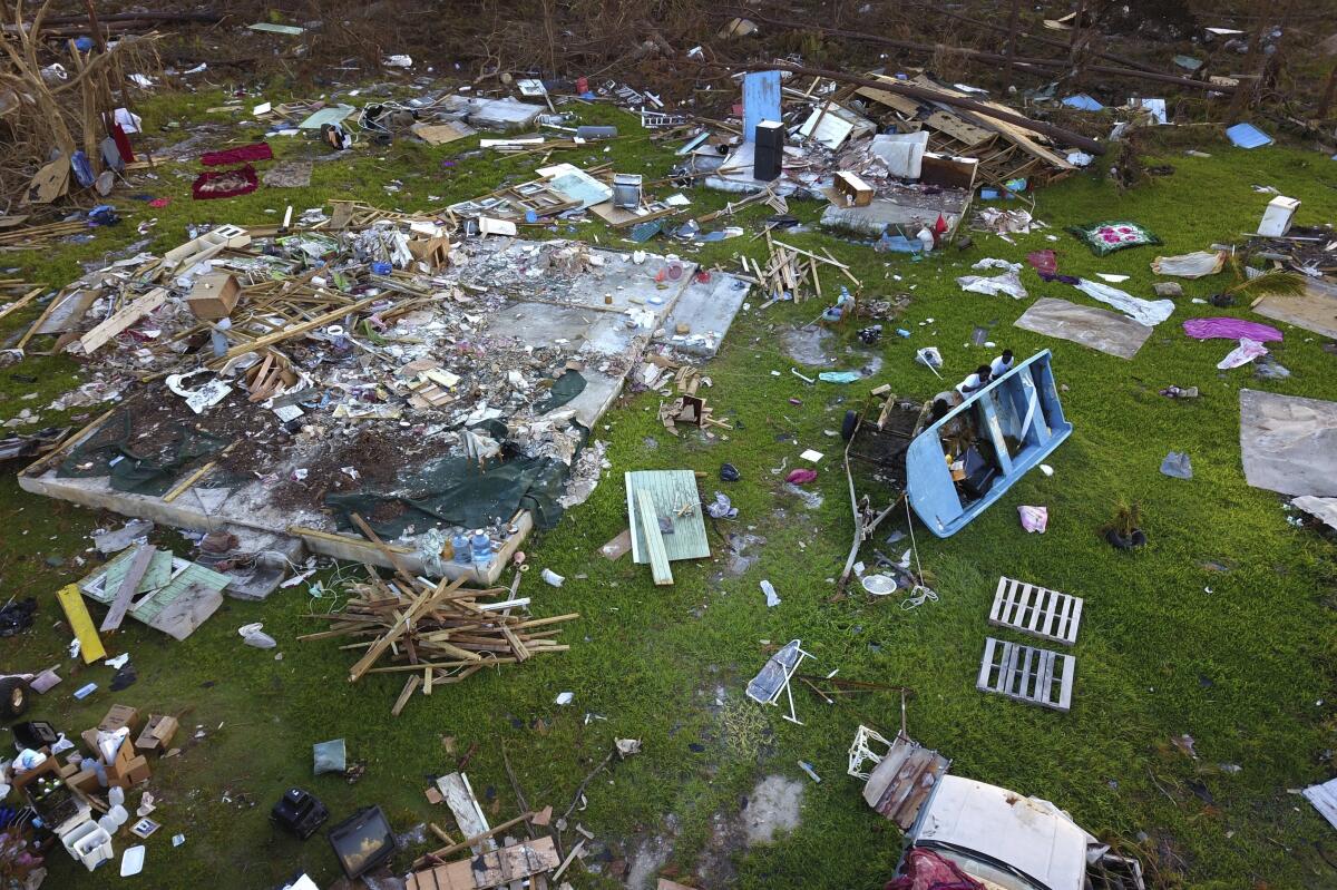 Dexter Edwards, center, his brother Nathanael Edwards, right, and his cousin Valentino Ingraham, push over a motorboat amid the rubble of Valentino's home, destroyed by Hurricane Dorian in Rocky Creek East End, Grand Bahama, Bahamas, Sunday, Sept. 8, 2019. Their families lived off the income from three boats they use for fishing and for providing tourist excursions from a pristine beachfront facing the turquoise Caribbean. (AP Photo/Ramon Espinosa)