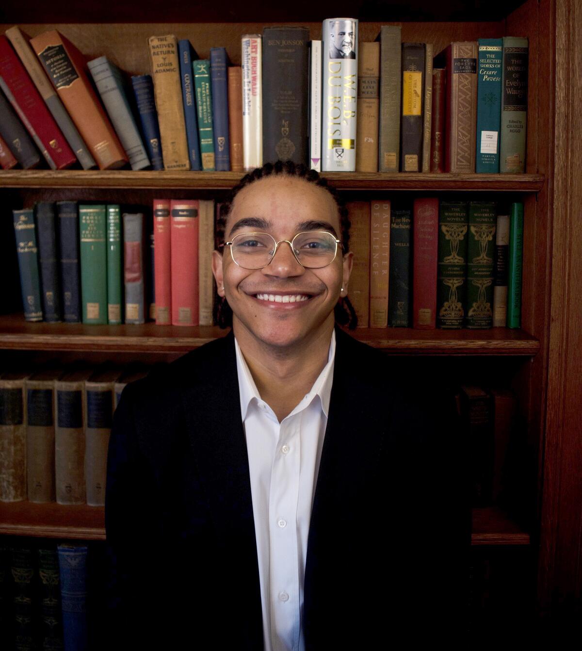 Quincy Diallo, a rising junior at Yale, poses for a portrait in front a full bookshelf.