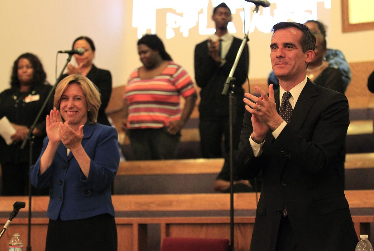 Mayoral candidates Wendy Gruel and Eric Garcetti applaud the crowd following their candidates forum Monday night at Macedonia Baptist Church.