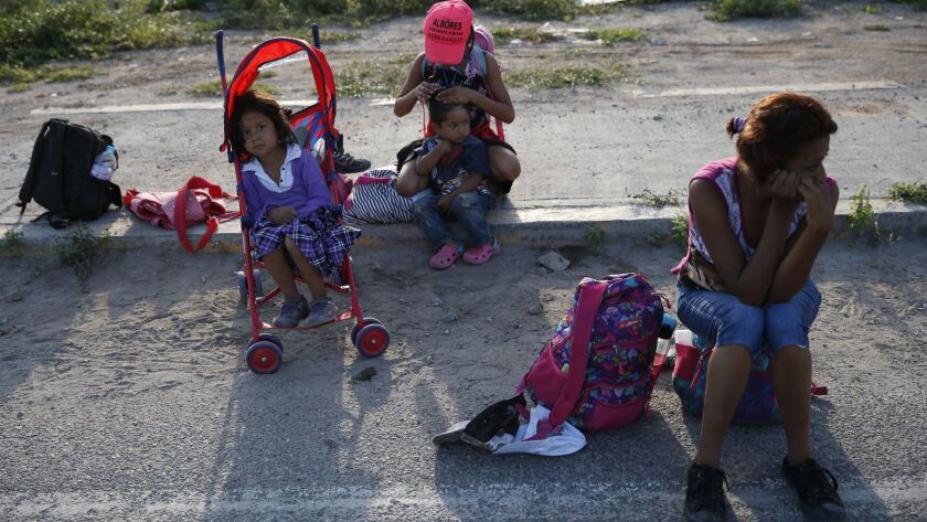 A woman and three children wait for a ride on the roadside, as a thousands-strong caravan of Central Americans hoping to reach the U.S. border moves onward from Juchitan, Oaxaca state, Mexico, Thursday, Nov. 1, 2018.