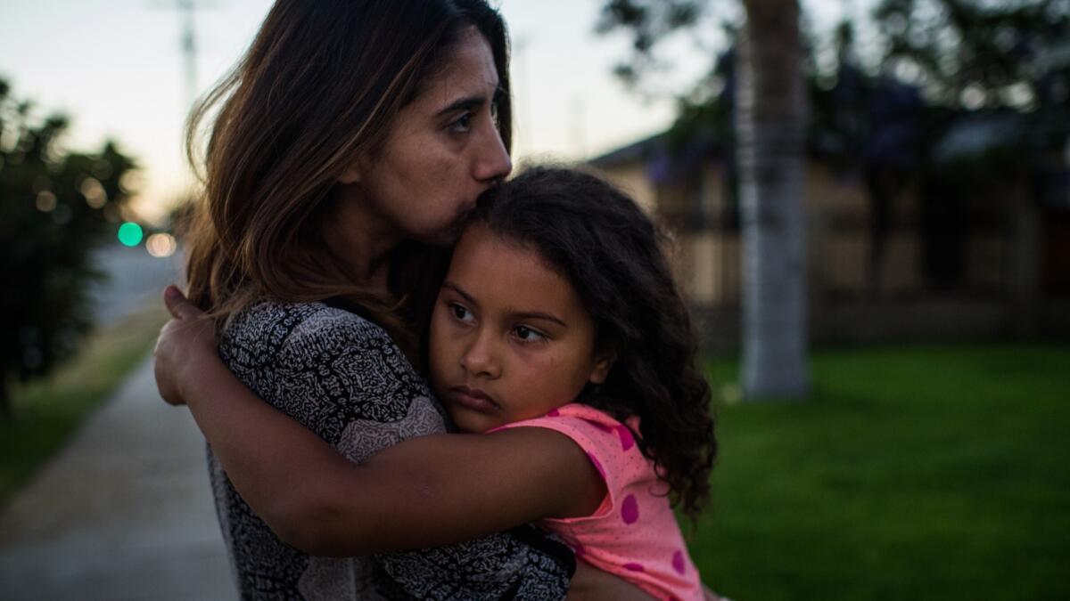 More than a week after the arrest of her father, Jose Luis Garcia, as he watered his lawn, Natalie Garcia tries to console her daughter Marley outside their home in Arleta.