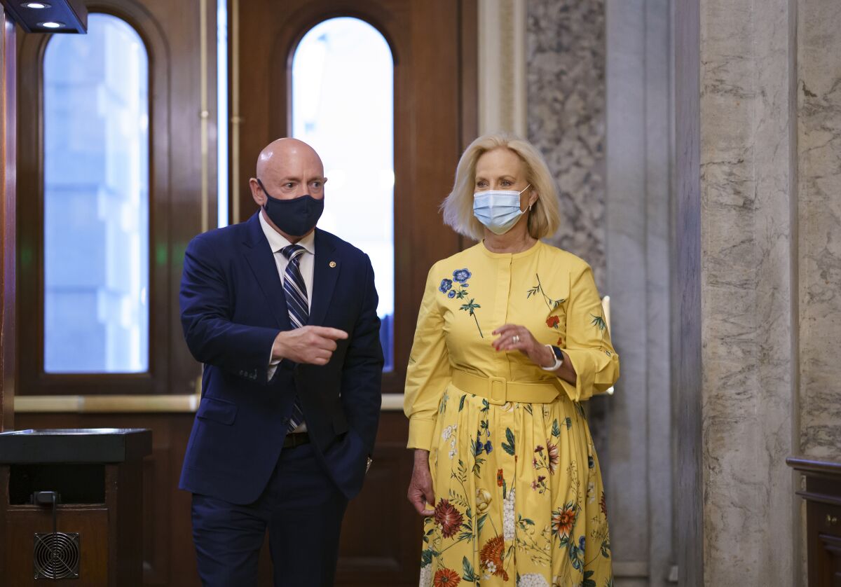 Sen. Mark Kelly, D-Ariz., is joined by Cindy McCain, right, the widow of the late Senator John McCain of Arizona, as Kelly arrives to deliver his maiden speech to the Senate, at the Capitol in Washington, Wednesday, Aug. 4, 2021. (AP Photo/J. Scott Applewhite)