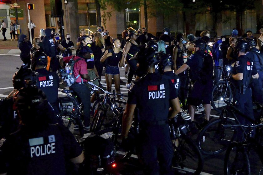 Protesters express themselves to Charlotte Mecklenburg Police bike officers at the intersection of Martin Luther King Jr. Blvd. and College Street in uptown Charlotte, N.C., on Friday, Aug. 21, 2020. (Jeff Siner/The Charlotte Observer via AP)