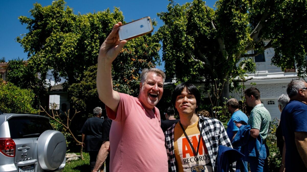 Jeffrey de Hart, left, snaps selfies with fellow Carpenters fans as they visit the music duo's home in Downey, Calif., on April 25, 2019