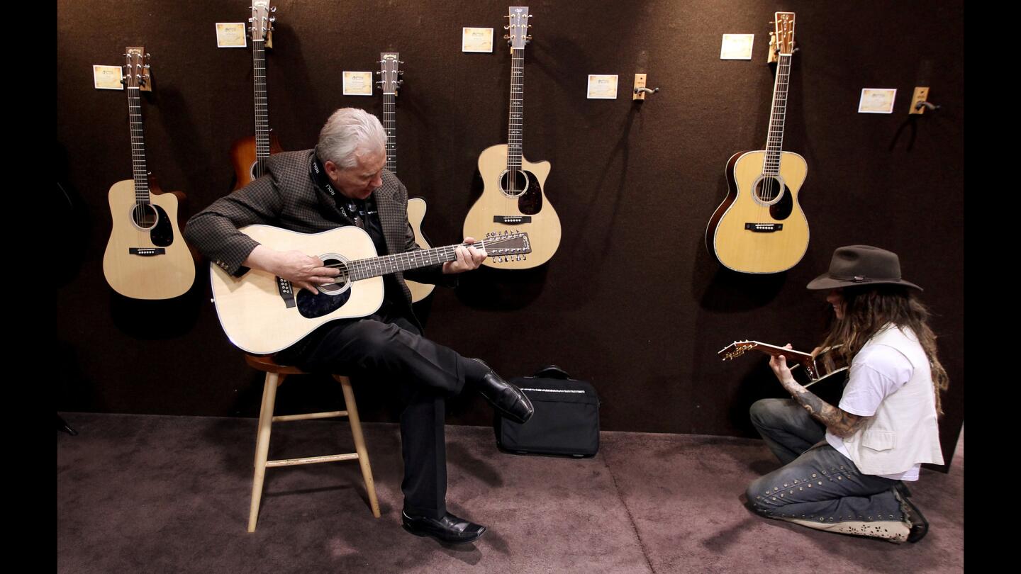 Musicians try out guitars at the booth of C. F. Martin & Co. during the annual National Assn. of Music Merchants show at the Anaheim Convention Center on Friday. The NAMM Show is the world's largest trade-only event for the music products industry, and is one of the two largest music product trade shows in the world.