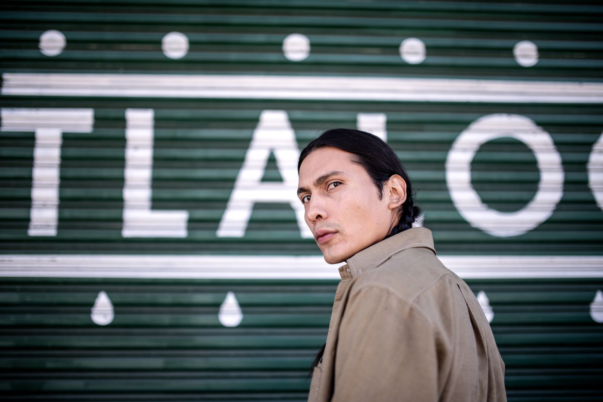 Ozzie Juarez in front of the green gate of Tlaloc Studios