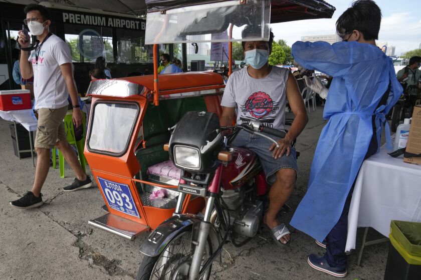 A pedicab driver is inoculated with China's Sinovac COVID-19 Vaccine in Manila, Philippines on Tuesday, June 22, 2021, in Manila, Philippines. The Philippine president has threatened to order the arrest of Filipinos who refuse the COVID-19 vaccination and told them to leave the country for hard-hit countries like India and the United States if they would not cooperate with massive efforts to end the pandemic. (AP Photo/Aaron Favila)