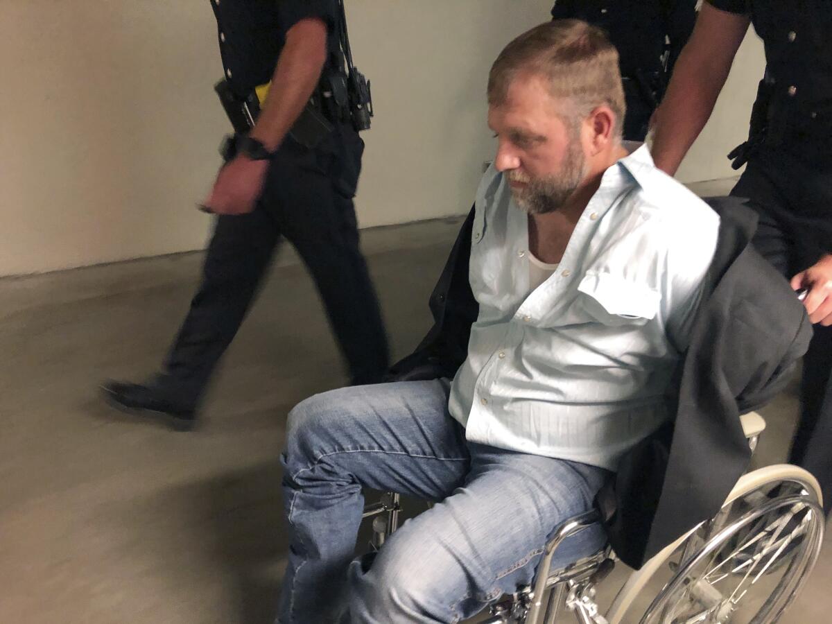 Ammon Bundy is pushed in a wheelchair. 