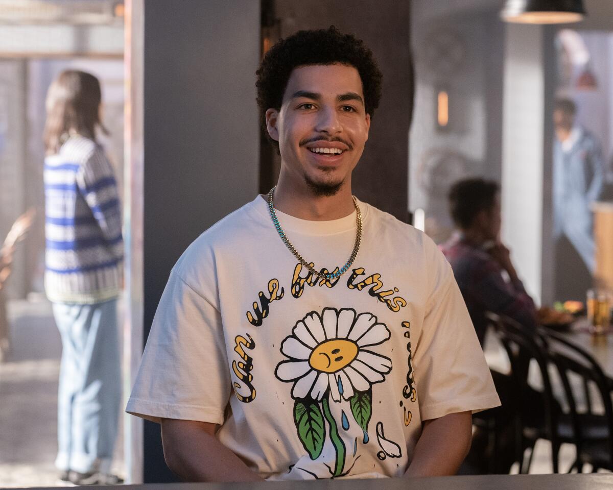 A college senior smiling in a T-shirt with a drawing of a white daisy on it.