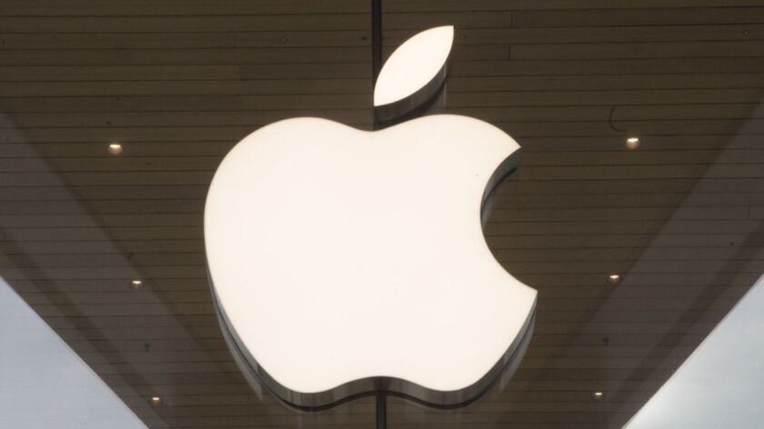 The white Apple logo is seen on a glass wall at an Apple store in Brooklyn, New York