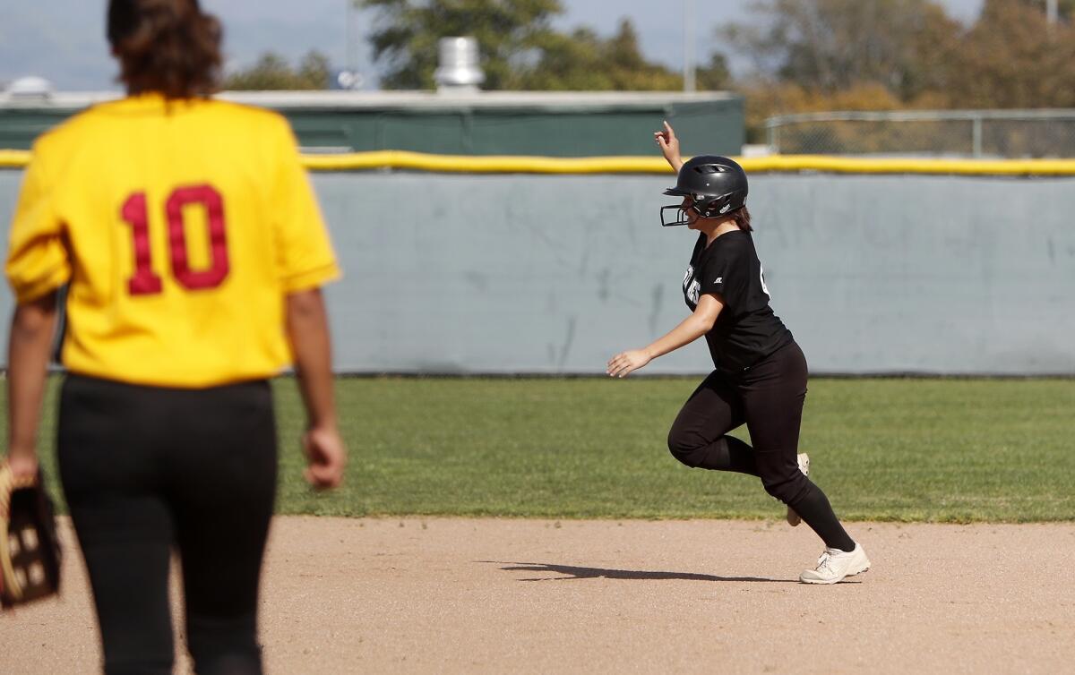 Costa Mesa High's Hailie Salyer, right, rounds the bases after hitting a home run as Estancia pitcher Dioselin Soto looks on in the second inning of an Orange Coast League game at Costa Mesa on Friday.