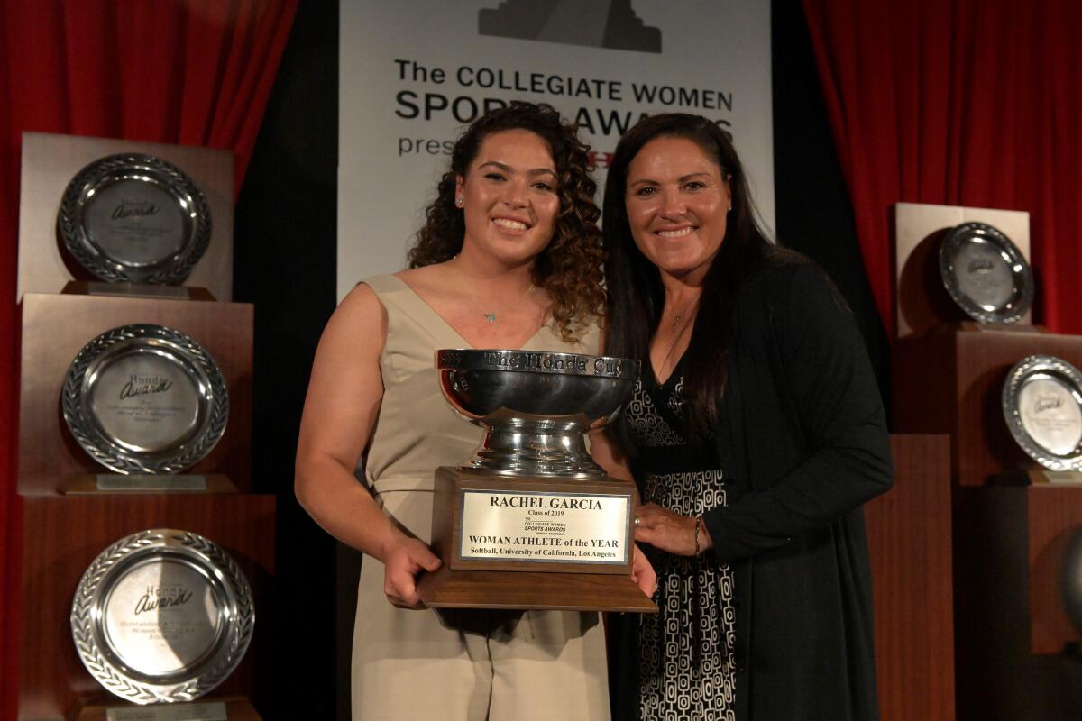 UCLA pitcher Rachel Garcia and former UCLA star Lisa Guerrero pose with a trophy 