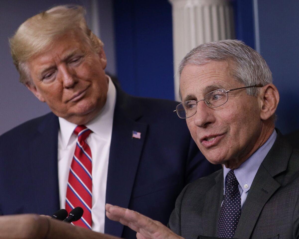 President Trump listens to Dr. Anthony Fauci, director of the National Institute of Allergy and Infectious Diseases, during a coronavirus briefing at the White House.