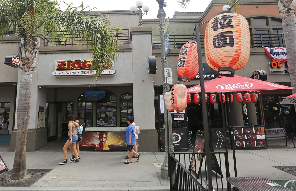 Visitors walk north past shops on Main Street in downtown Huntington Beach in September 2022.