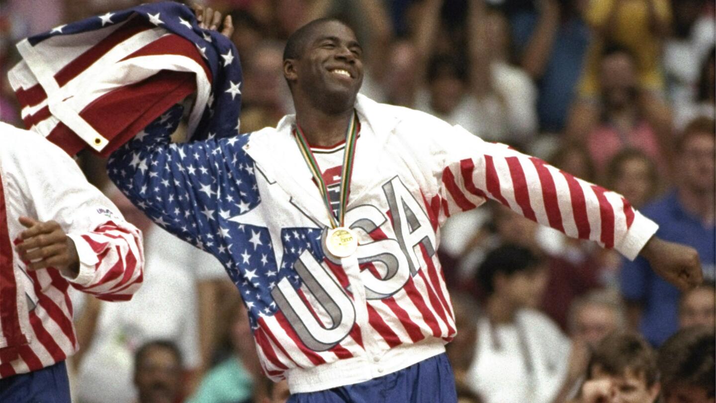 Magic Johnson waves the American flag while celebrating during the men's basketball gold medal ceremony at the 1992 Barcelona Olympic Games.