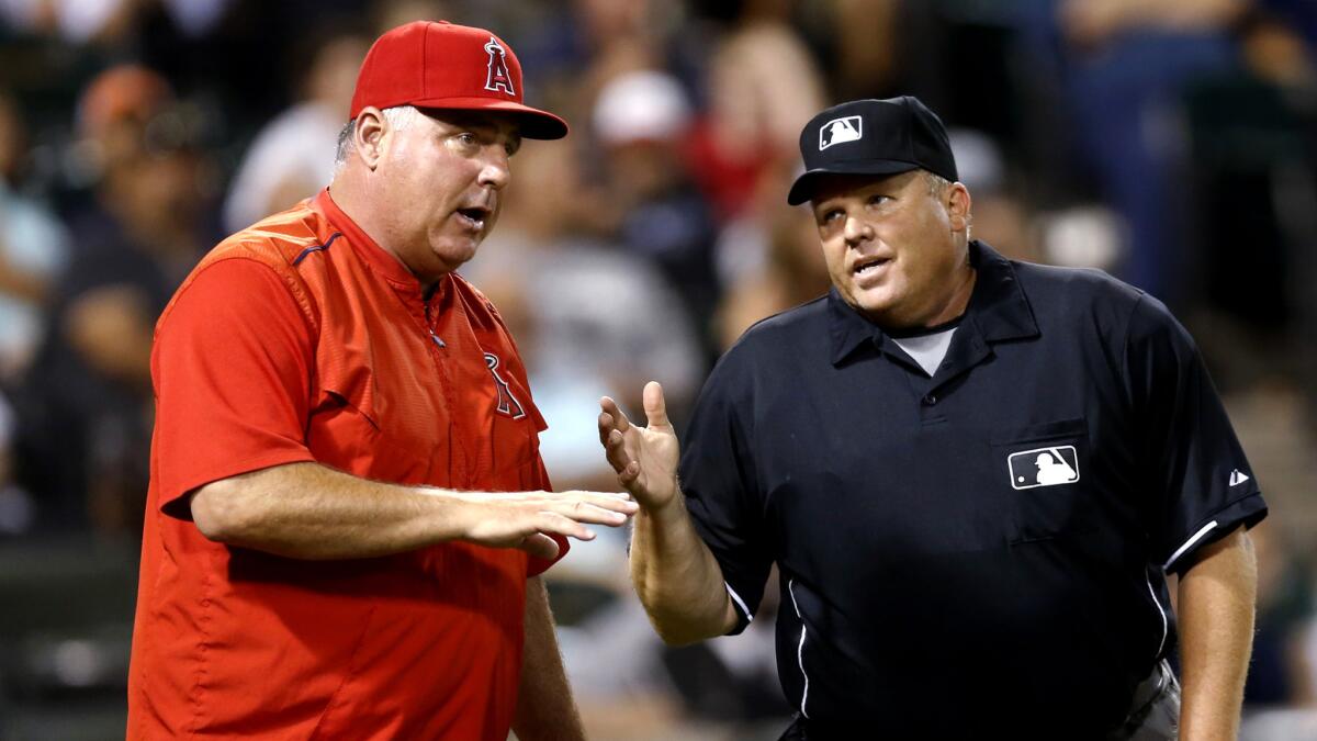 Los Angeles Angels manager Mike Scioscia, left, talks with home plate umpire Fieldin Culbreth during the ninth inning of a baseball game against the Chicago White Sox on Wednesday, Aug. 12, 2015, in Chicago. (AP Photo/Charles Rex Arbogast)