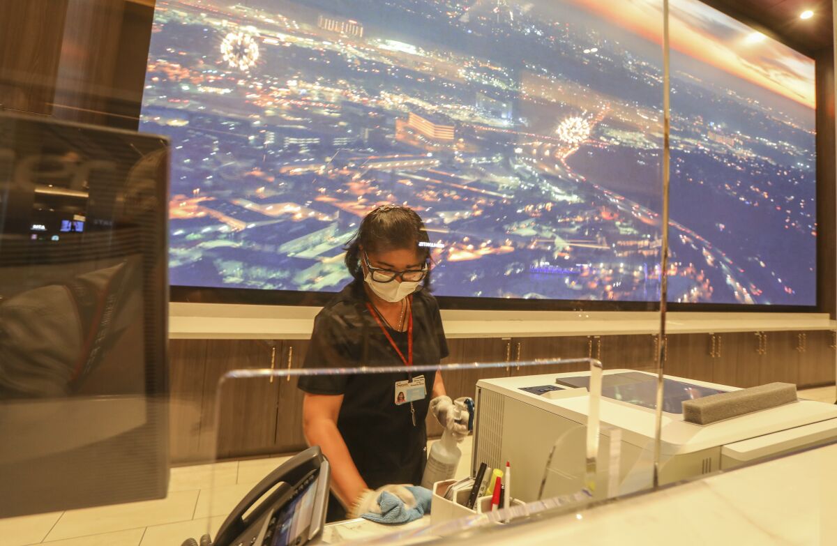With a plexiglass shield at the front desk to ensure safety for guests, Jane Santo Domingo, an environmental services worker, cleans and sanitizes the front desk area at Sycuan Casino on May 15, 2020 in El Cajon, California.
