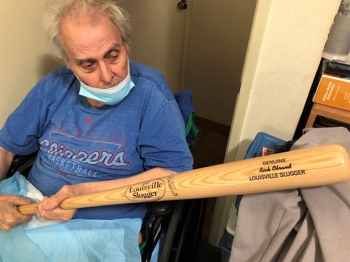 Rick Obrand holds his own autograph Louisville Slugger bat at his home.