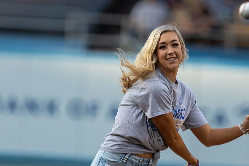 LOS ANGELES, CALIF. -- MONDAY, JUNE 17, 2019: UCLA softball player Stevie Wisz throws out the ceremonial first pitch during the Dodgers vs Giants at Dodger Stadium in Los Angeles, Calif., on June 17, 2019. Wisz postponed her fourth open heart surgery until after her season the season, so she could compete for the national title with the Bruins. Catching the first pitch was Dodgers pitcher Kenley Jansen, who also has heart issues. (Allen J. Schaben / Los Angeles Times)