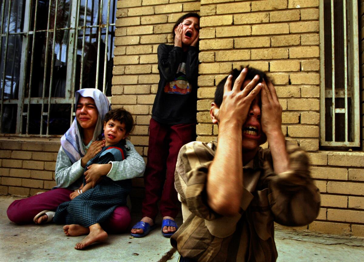 Four people crying with hands on their faces in front of a brick building