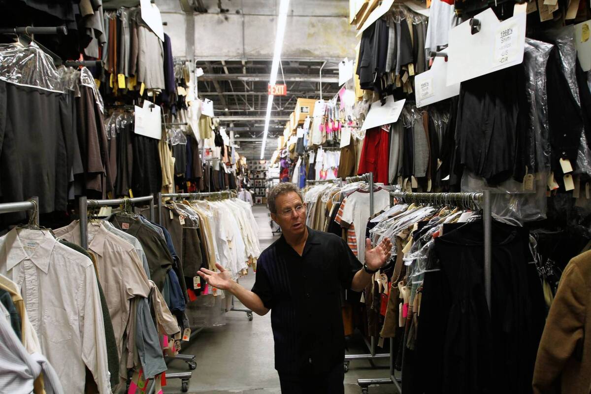 Eddie Marks, president of Western Costume, stands amid rows of garments that are sorted by decade.