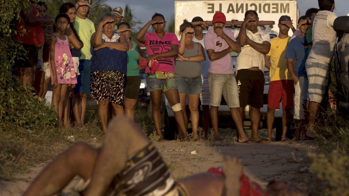 Residents look at the body of a man killed during a confrontation between Sindicato do Crime and Primeiro Comando da Capital gang members in Natal, Brazil, one of the most violent cities in the world.