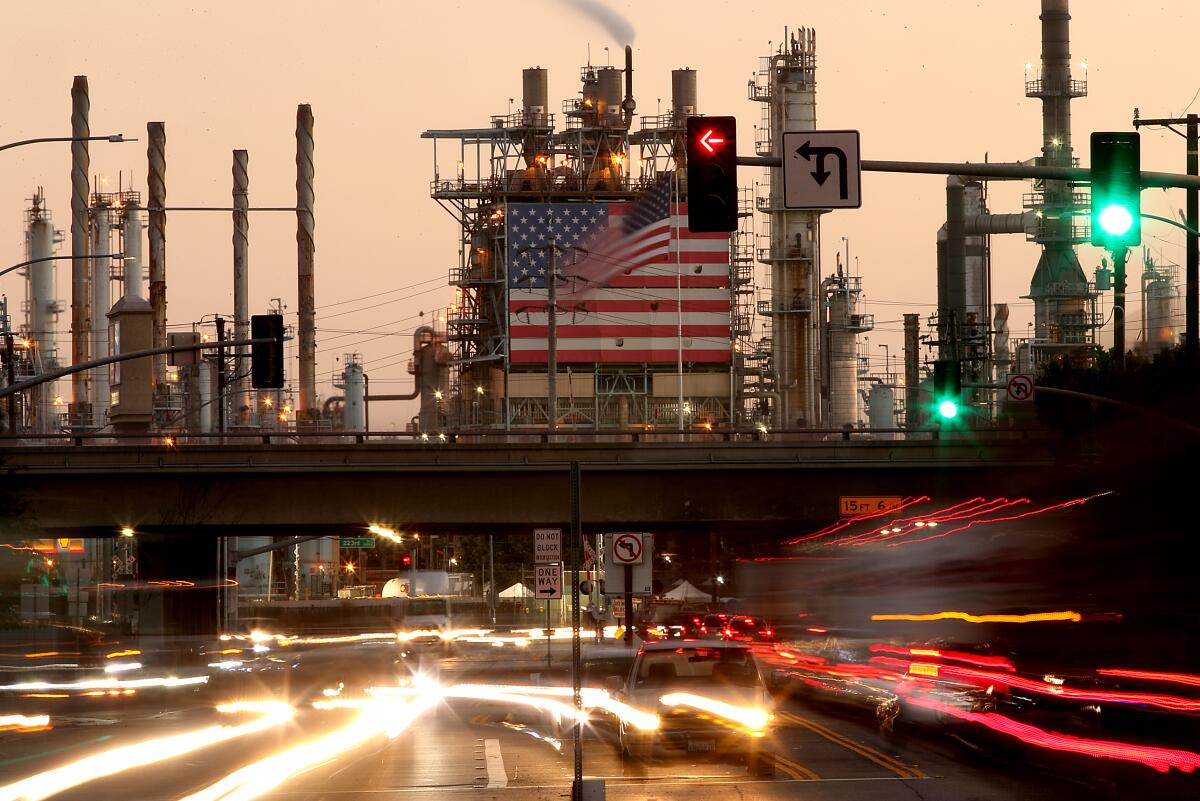 Traffic streams past the Marathon oil refinery in Carson.