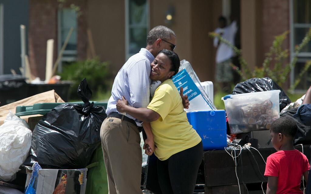 President Barack Obama hugs Marlene Sanders as he visits with with residents of Castle Place, a flood-damaged area of Baton Rouge, La., Tuesday, Aug. 23.