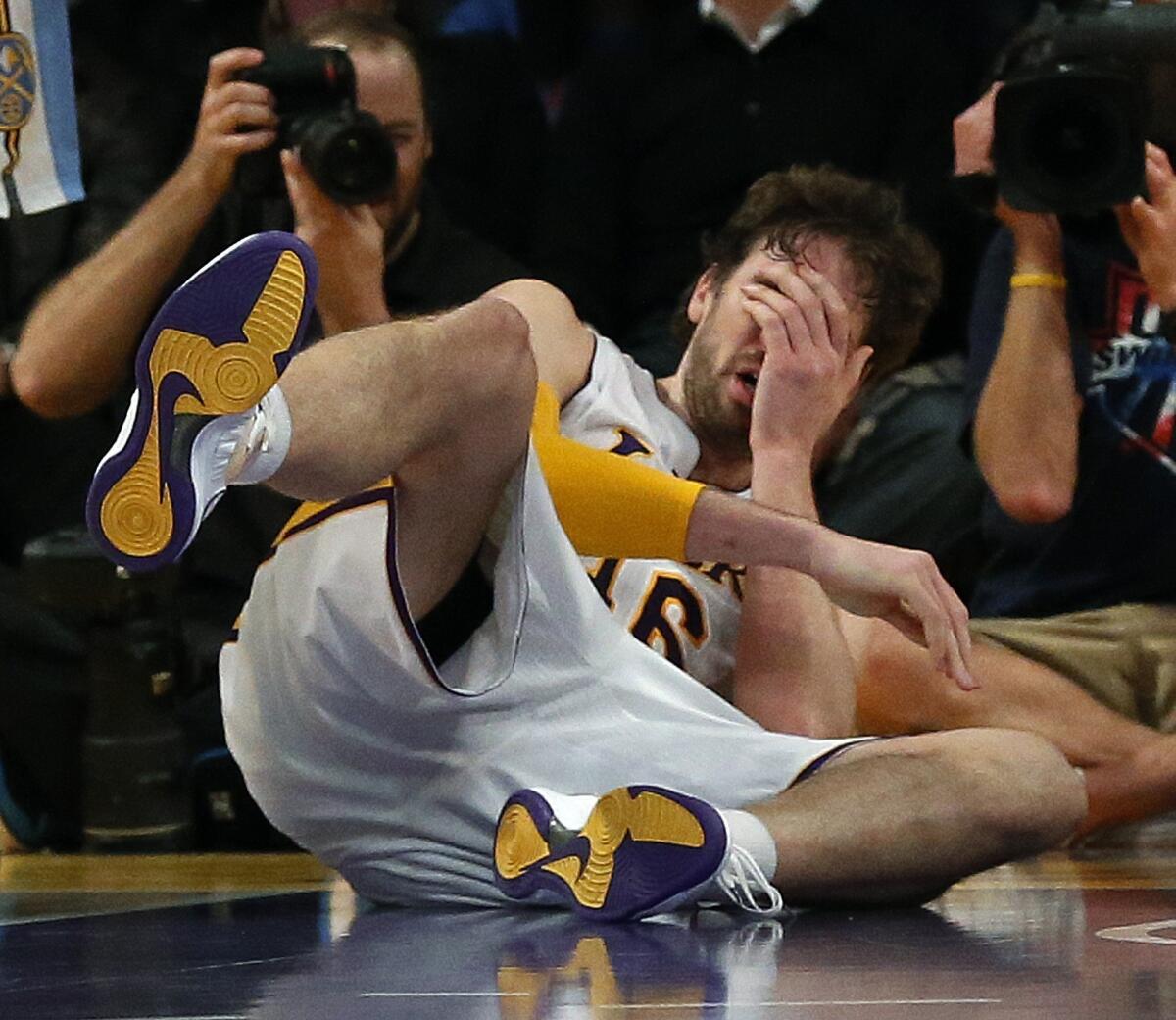 Pau Gasol falls to the floor after he is smacked in the nose by the Nuggets' JaVale McGee late in the fourth quarter of the Lakers' loss to Denver, 112-105.