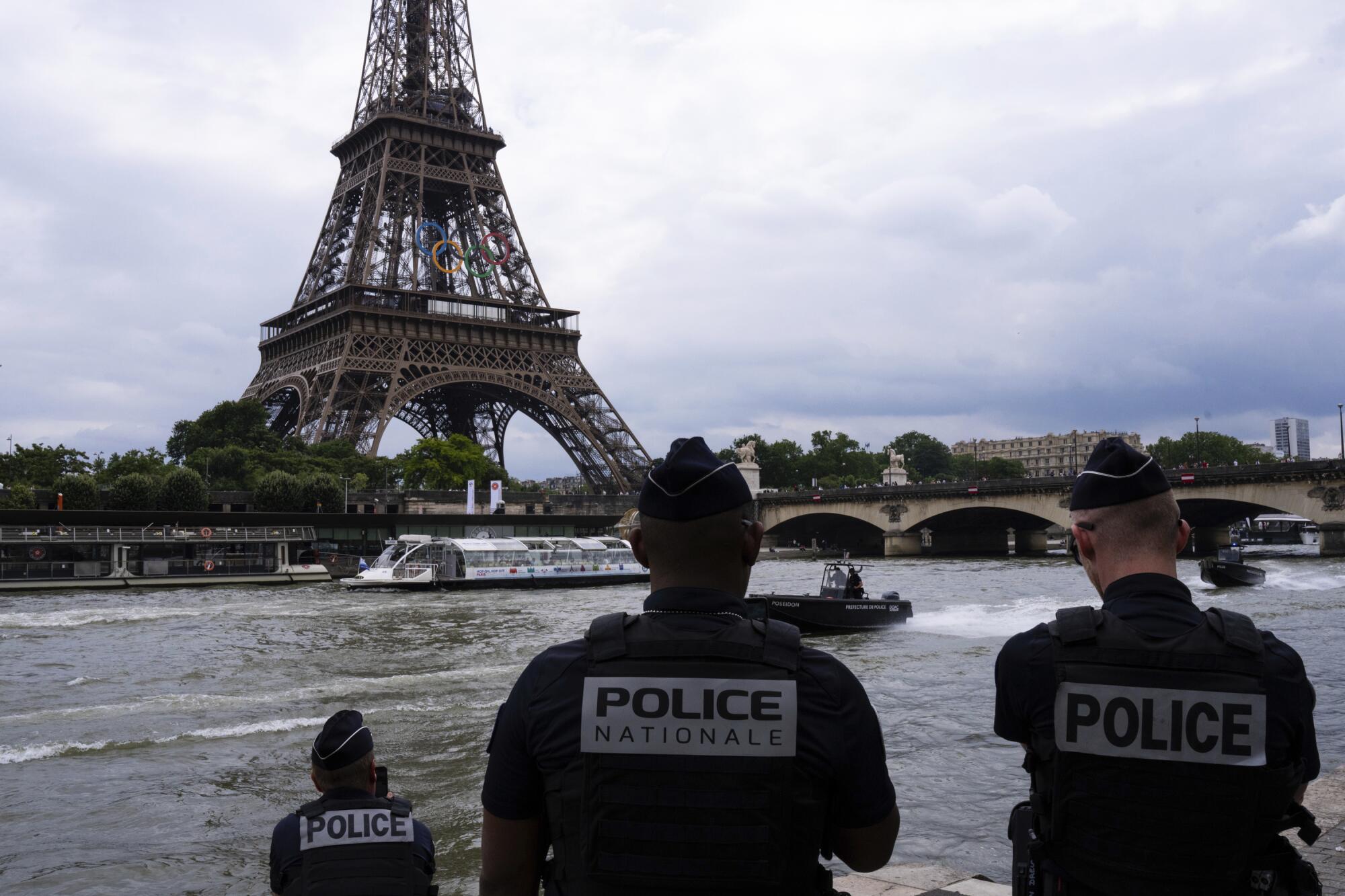 Police officers watch river police boats patroling past the Eiffel Tower on the Seine River in Paris on July 2.
