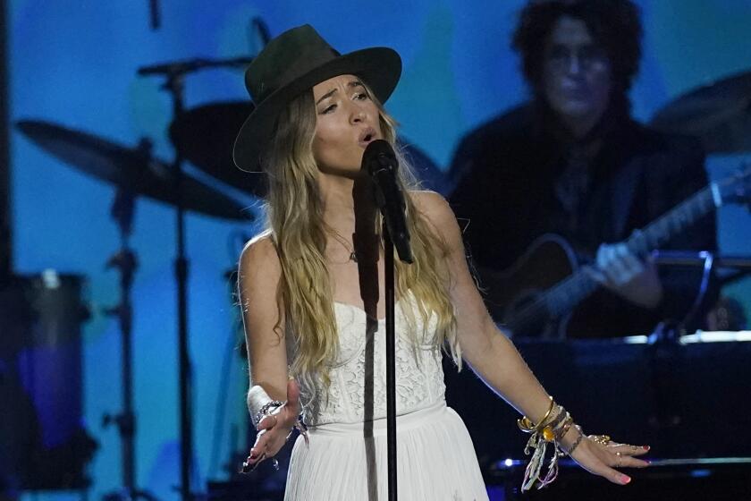 Lauren Daigle wears a large-brimmed hat while singing onstage