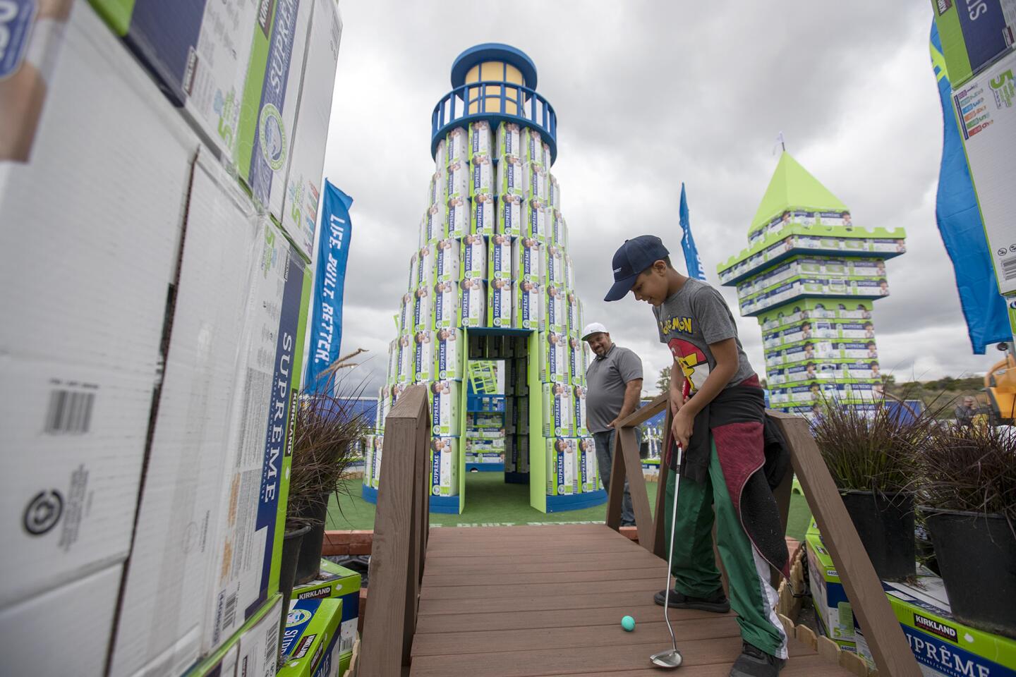 Nathan Ramirez Sr., left, watches his son Nathan Jr. play in the Meritage Homes' "Best in Show"-winning miniature golf course structure during the 5th Annual Builders for Babies competition at Anaheim Stadium.