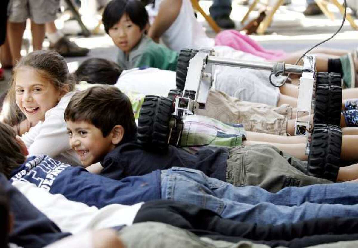 A small rover crawls over children during the JPL Open House in La Canada Flintridge in 2010.