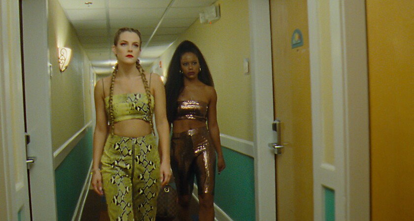 Two young women walk down a hotel corridor
