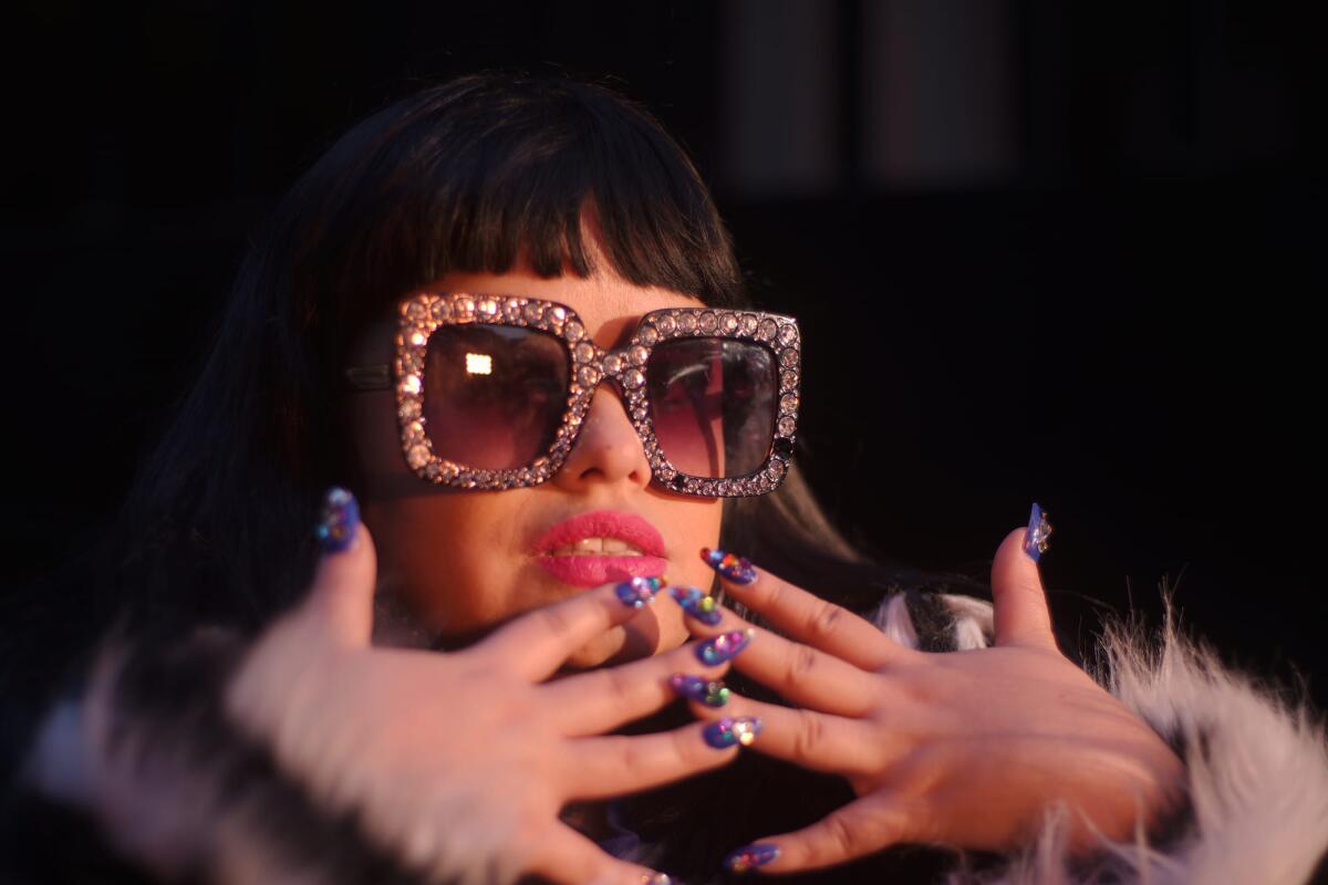 A young woman in bling'd out shades shows off her manicure