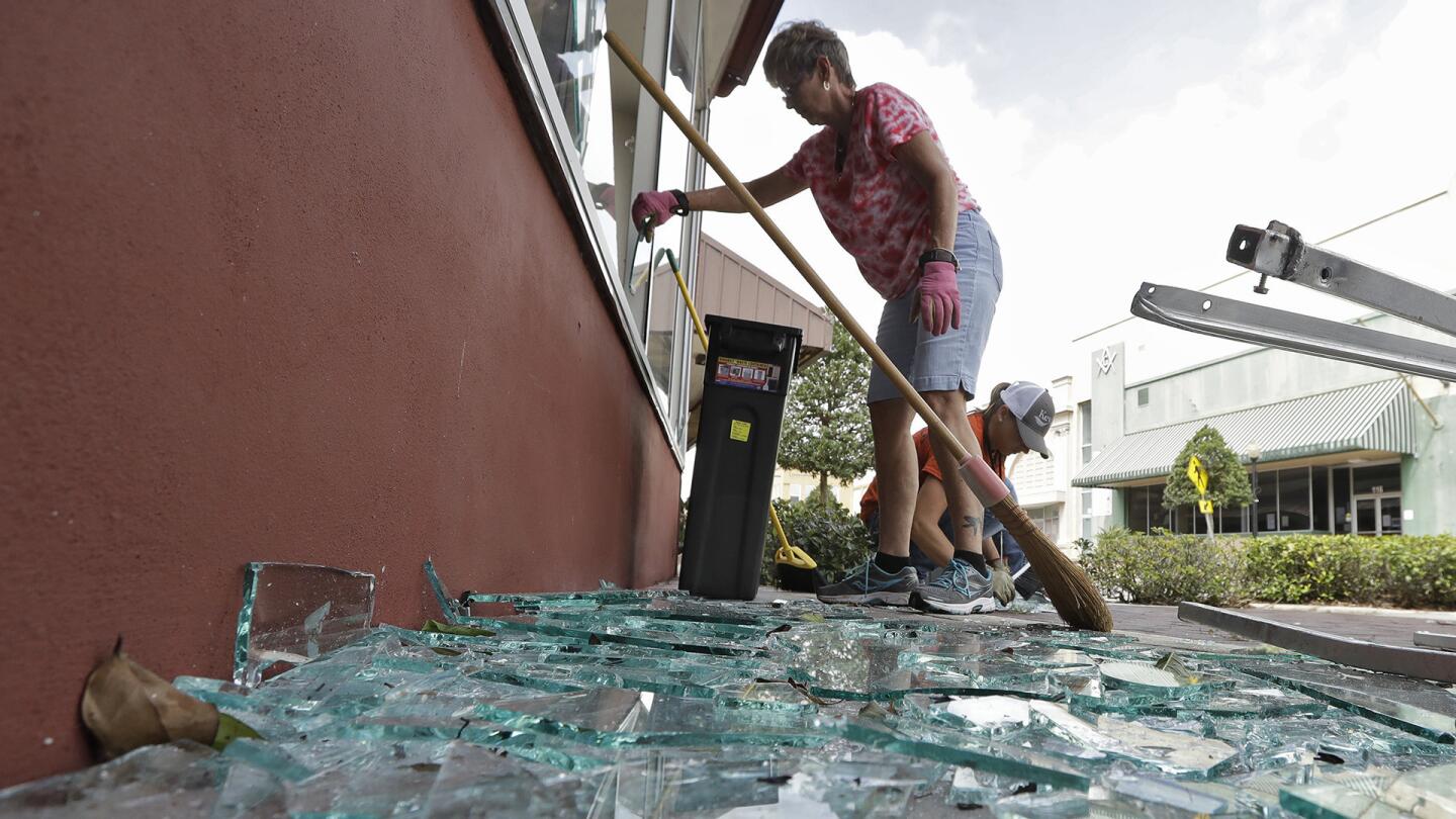 Building owner Catharine Taylor Woods, front, and Jessica Newman, of the City of Wauchula clean up broke glass after an awning blew off in Hurricane Irma and broke several windows early Monday, Sept. 11, 2017, in Wauchula, Fla.