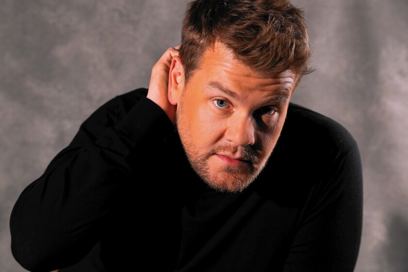 James Corden poses in a black sweater