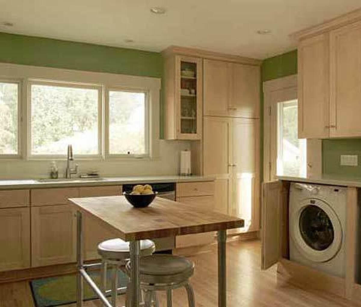 IN HIDING: A washer and dryer are neatly tucked into a cabinet in the kitchen, above. At right, a wide opening was created between the kitchen and dining rooms and framed with molding.
