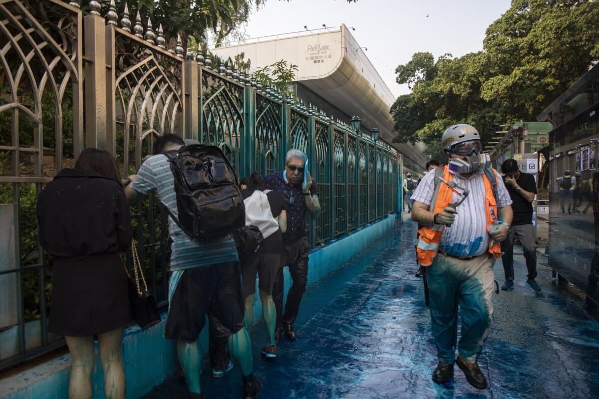 People react after sprayed with blue-dyed water by a police riot-control vehicle during a protest outside the Kowloon Mosque in Hong Kong. Hong Kong officials apologized to leaders of the Kowloon Mosque afterward.