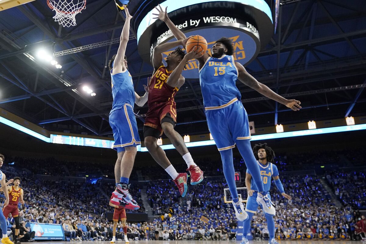 USC guard Reese Dixon-Waters shoots between UCLA guard Jaime Jaquez Jr. and center Myles Johnson.