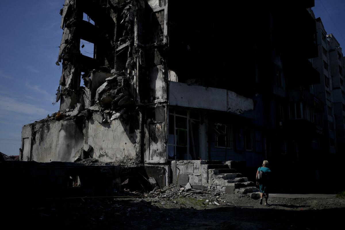 Una mujer camina junto a un edificio destruido por los bombardeos rusos en Borodyanka