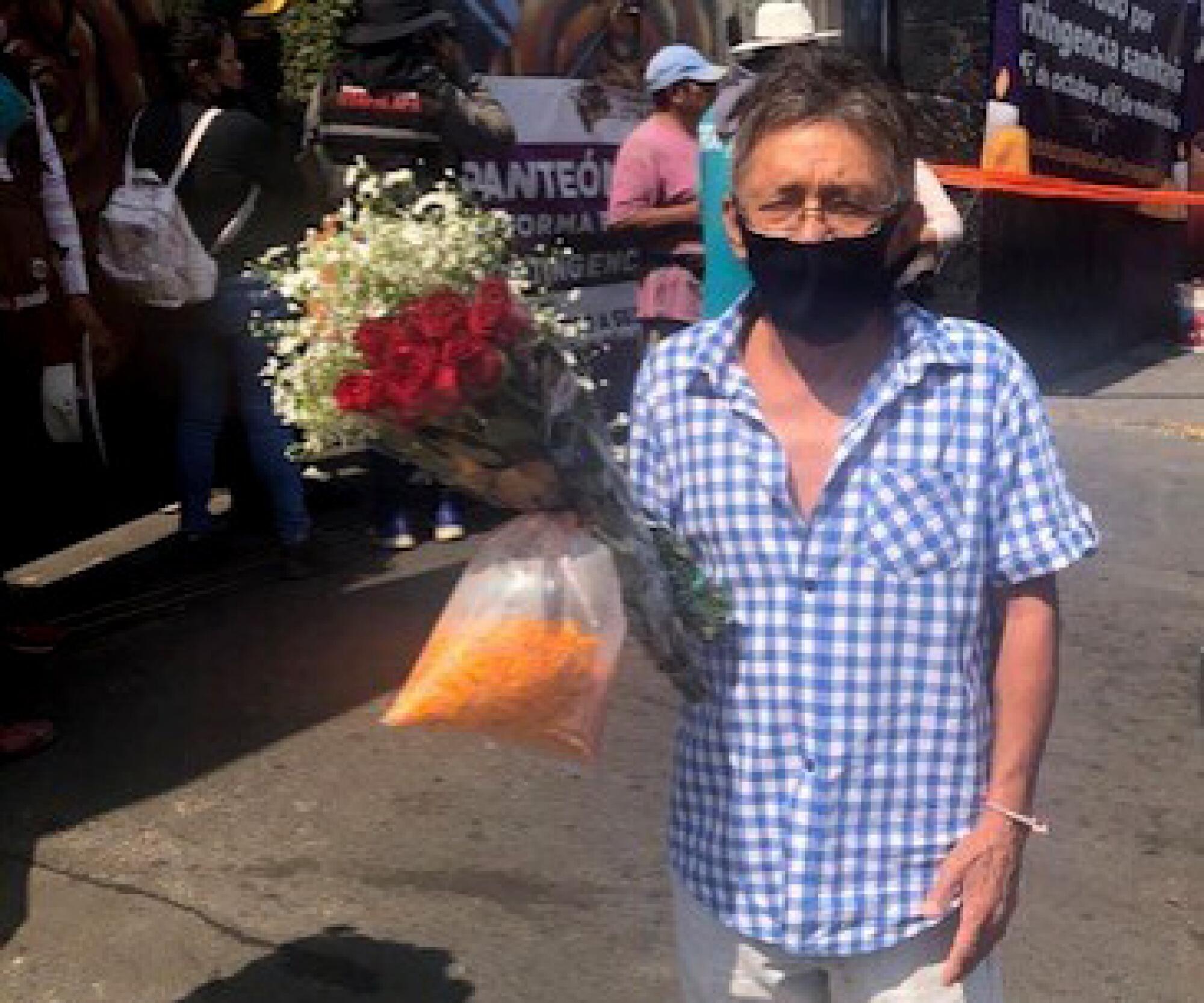 A man in a mask holds flowers