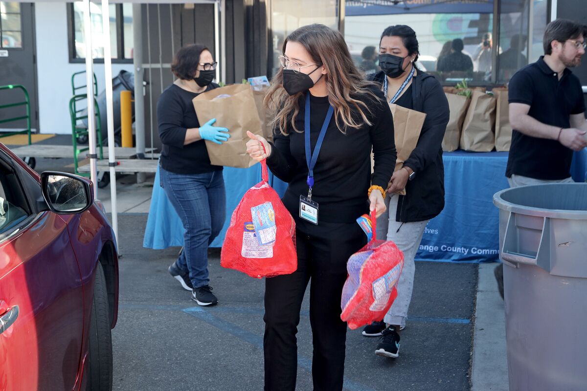 Anna Schroeder carries two whole turkeys as she helps distribute Thanksgiving food in Costa Mesa.