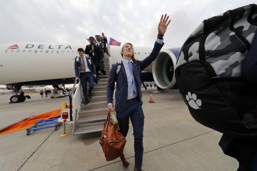 Clemson quarterback Trevor Lawrence waves as he arrives with the team for the NCAA College Football Playoff title game in New Orleans, Friday, Jan. 10, 2020. Clemson is scheduled to play LSU on Monday. (AP Photo/Gerald Herbert)