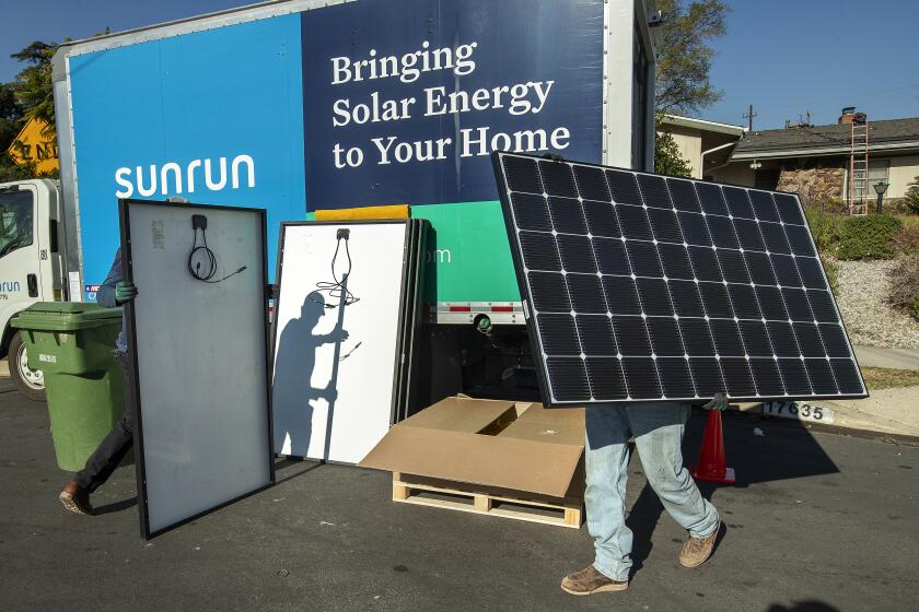 GRANADA HILLS, CA - JANUARY 04, 2020: Aaron Newsom, left, an installer for the solar company, Sunrun, and Tim McKibben, a senior installer, prepare solar panels to be installed on the roof of a home in Granada Hills. (Mel Melcon / Los Angeles Times)