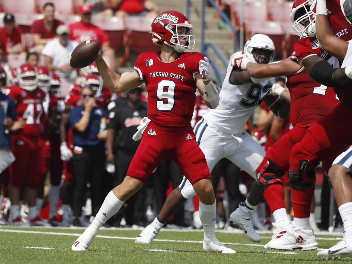 Fresno State quarterback Jake Haener throws a pass past Connecticut defenders Aug. 28, 2021.