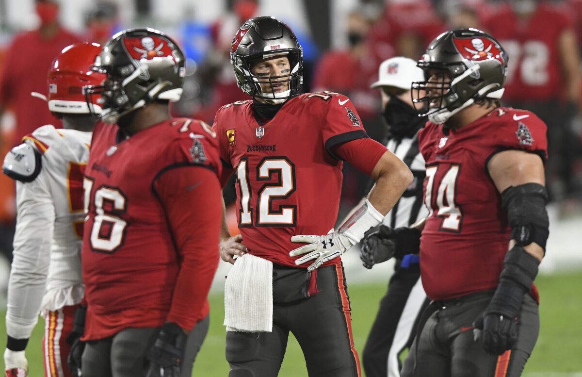 Tampa Bay Buccaneers quarterback Tom Brady is on the field with teammates around him.